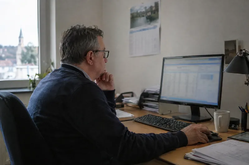 Ein Regionalleiter sitzt im Büro vor einem Bildschirm mit Auswertungen.