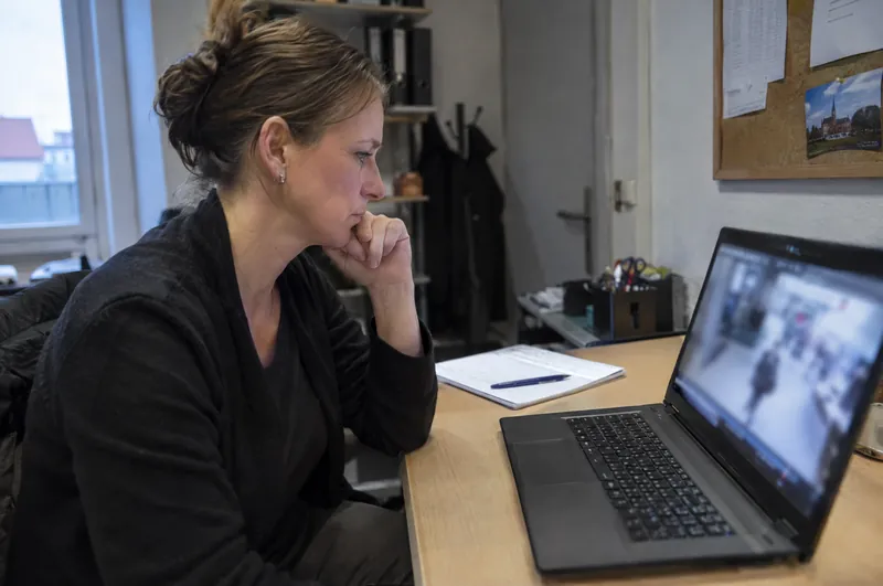 Eine Filialleiterin prüft im Büro einen Videoausschnitt auf dem Laptop.