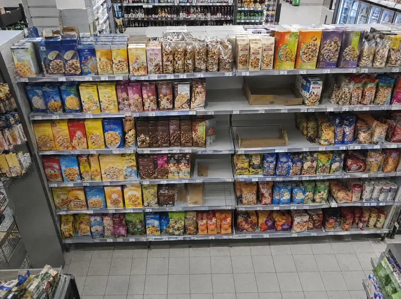 Blick von oben auf die volle Front eines Supermarktregals, auf den mittleren Böden fehlen einzelne Packungen.